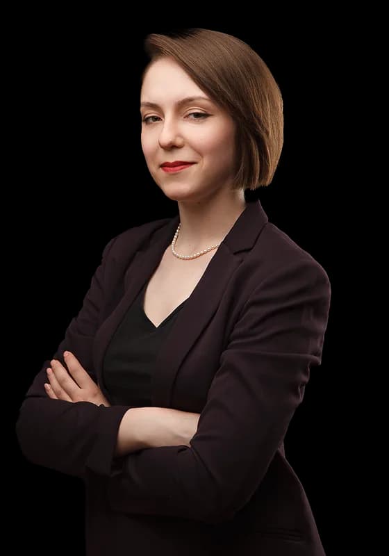 A teacher with a dark bob in a burgundy blazer, arms folded.