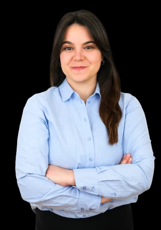 A teacher in a pale blue shirt, arms folded, smiling at the camera.